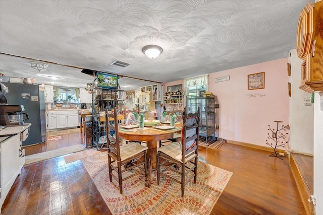 dining area with a textured ceiling and light hardwood / wood-style flooring