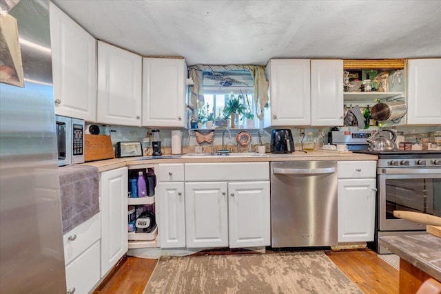 kitchen with white cabinets, sink, light wood-type flooring, and stainless steel appliances