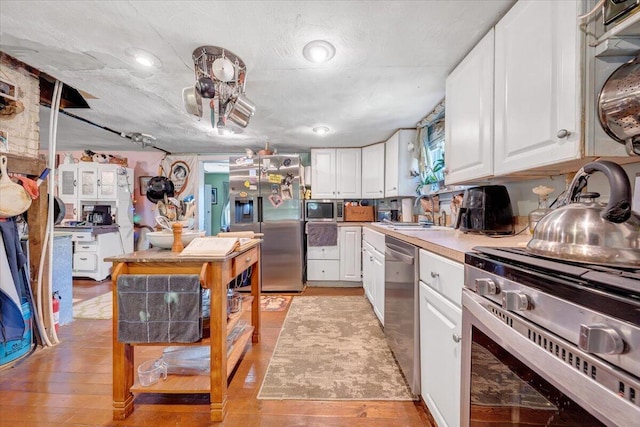 kitchen featuring white cabinets, sink, light wood-type flooring, a textured ceiling, and appliances with stainless steel finishes