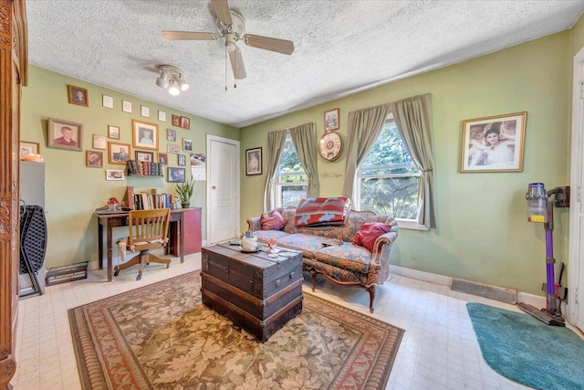 living area featuring ceiling fan and a textured ceiling