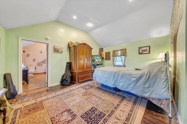 bedroom featuring ensuite bath, wood-type flooring, and vaulted ceiling