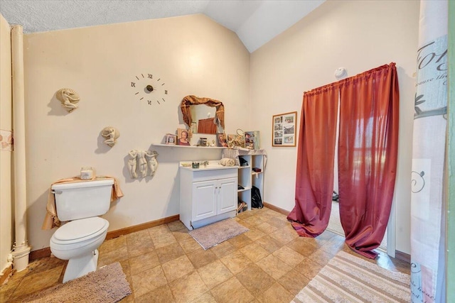 bathroom featuring a textured ceiling, vanity, lofted ceiling, and toilet