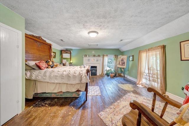 bedroom with vaulted ceiling, a textured ceiling, and hardwood / wood-style flooring