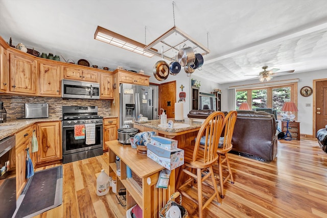 kitchen with decorative backsplash, light stone counters, stainless steel appliances, ceiling fan, and light hardwood / wood-style flooring