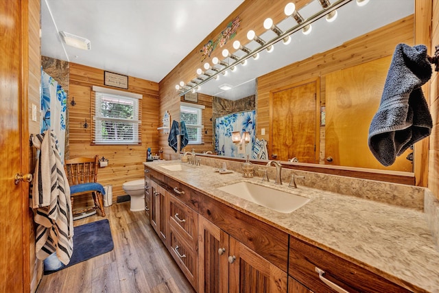 bathroom with hardwood / wood-style floors, vanity, toilet, and wooden walls