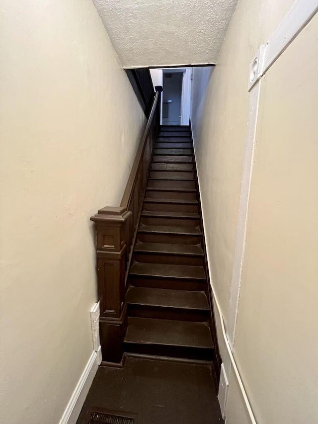 staircase with a textured ceiling