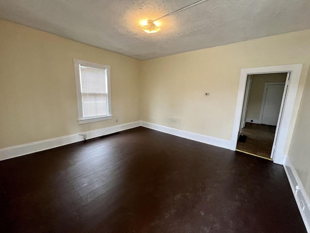 empty room featuring dark hardwood / wood-style flooring and a textured ceiling