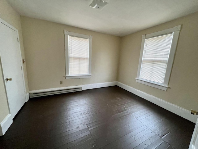 unfurnished room with dark hardwood / wood-style floors and a baseboard heating unit