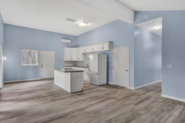 kitchen featuring a center island, white fridge, white cabinetry, and light hardwood / wood-style floors