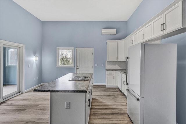 kitchen with a center island, a wall unit AC, white fridge, decorative backsplash, and white cabinets