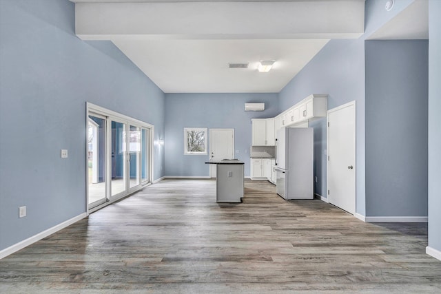 306 Carey Ave, Salem, VA 24153 - kitchen with white cabinetry, white refrigerator, hardwood / wood-style floors, a towering ceiling, and a kitchen island with sink