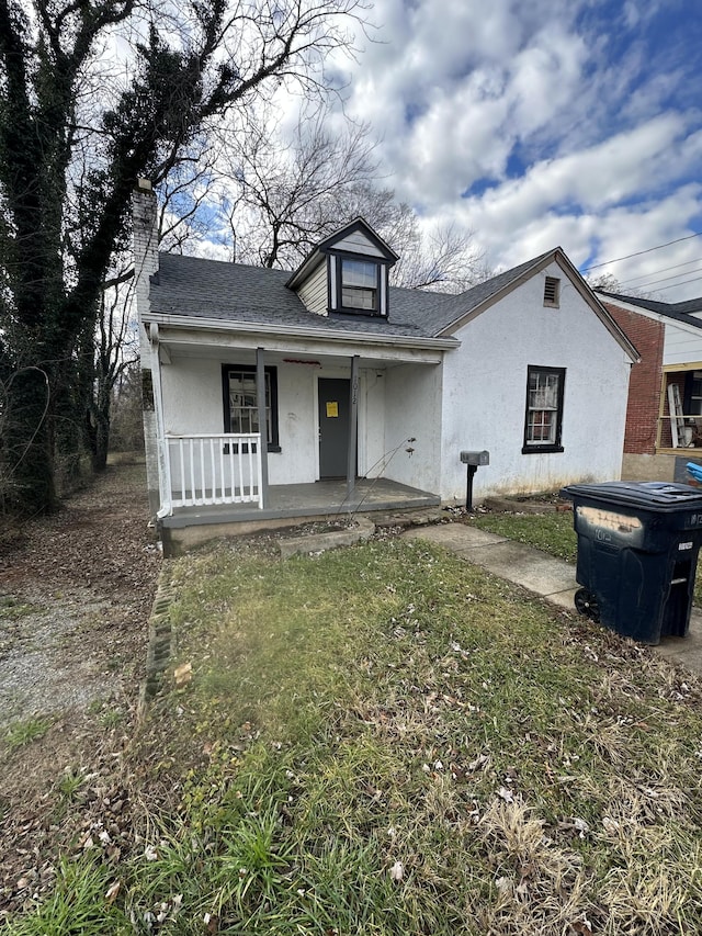 bungalow featuring covered porch and a front yard