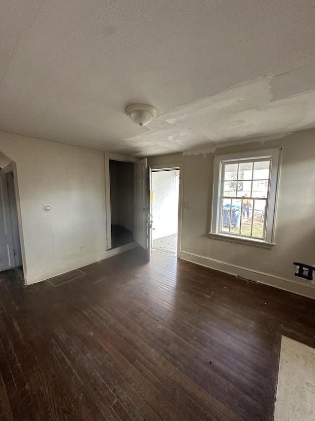 empty room with a textured ceiling and dark wood-type flooring