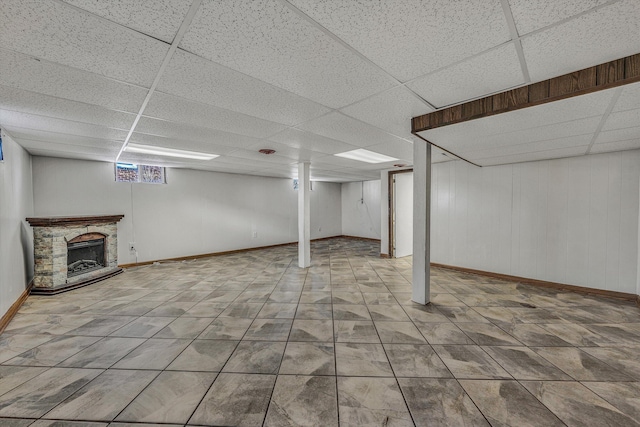 basement with a paneled ceiling and a stone fireplace