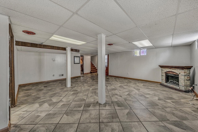 basement with a fireplace and a drop ceiling