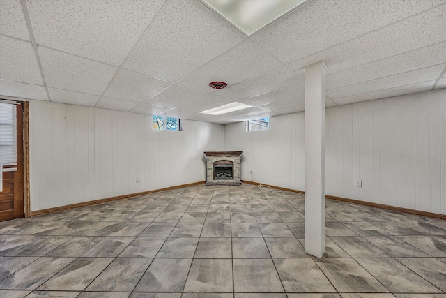 basement with a drop ceiling and wooden walls