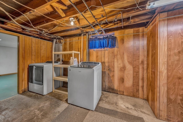 clothes washing area featuring wood walls and washer and clothes dryer