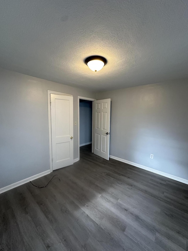 unfurnished room with a textured ceiling and dark hardwood / wood-style floors