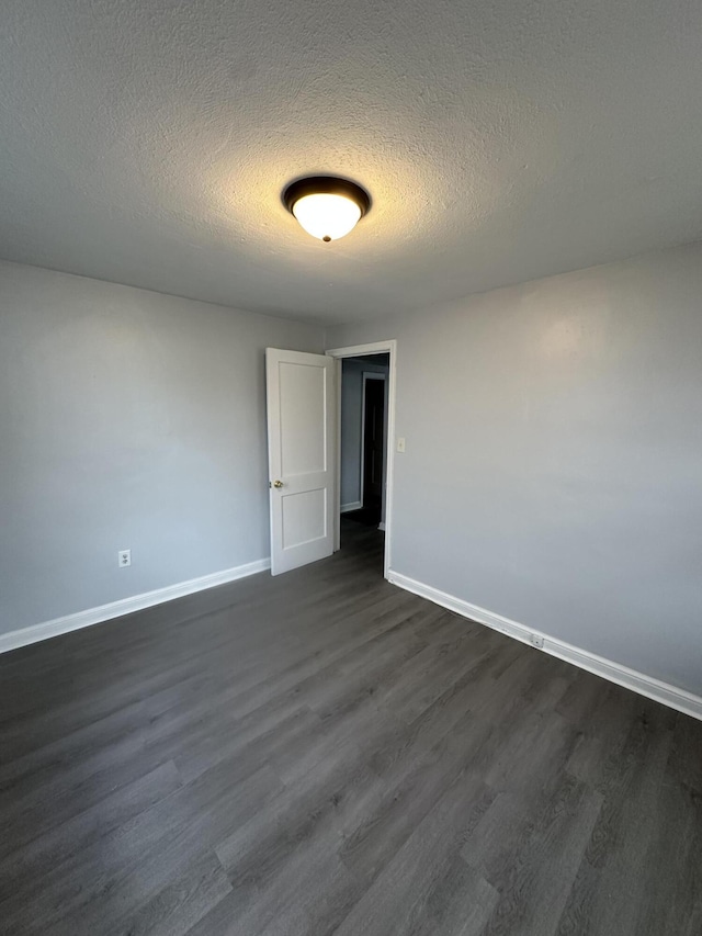 spare room with a textured ceiling and dark hardwood / wood-style floors