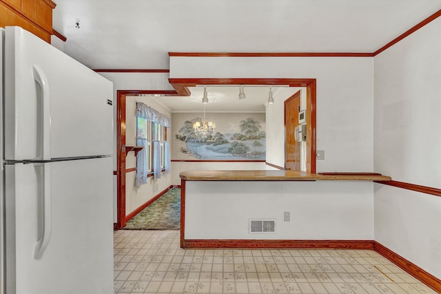 kitchen featuring white fridge, ornamental molding, hanging light fixtures, and a chandelier