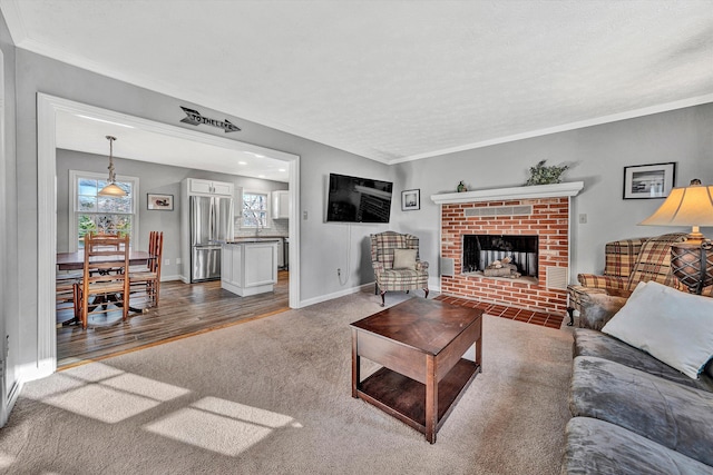 living room with a brick fireplace, carpet flooring, and crown molding