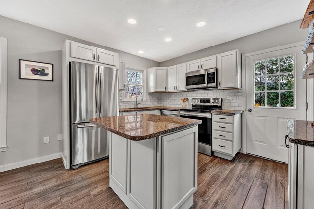 kitchen featuring a kitchen island, dark wood-type flooring, white cabinetry, stainless steel appliances, and sink