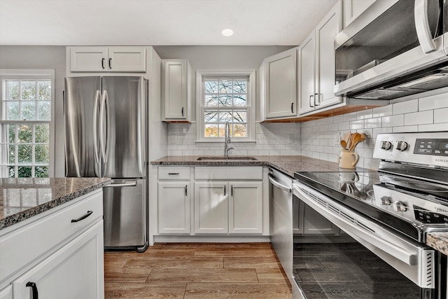 kitchen featuring sink, white cabinetry, appliances with stainless steel finishes, and dark stone counters