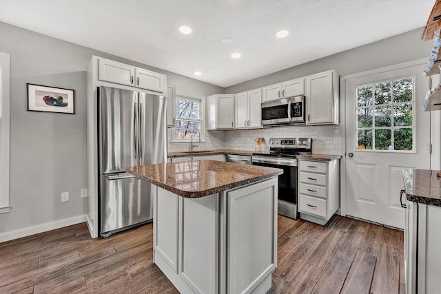 kitchen with white cabinetry, decorative backsplash, a sink, appliances with stainless steel finishes, and dark wood-type flooring