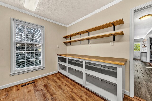 details featuring wood finished floors, ornamental molding, baseboards, visible vents, and a textured ceiling