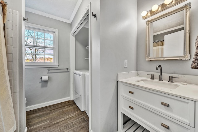 bathroom featuring vanity, washing machine and dryer, crown molding, and hardwood / wood-style flooring