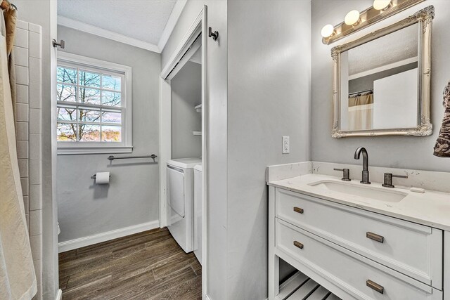 bathroom with vanity, baseboards, ornamental molding, washer and dryer, and wood finished floors