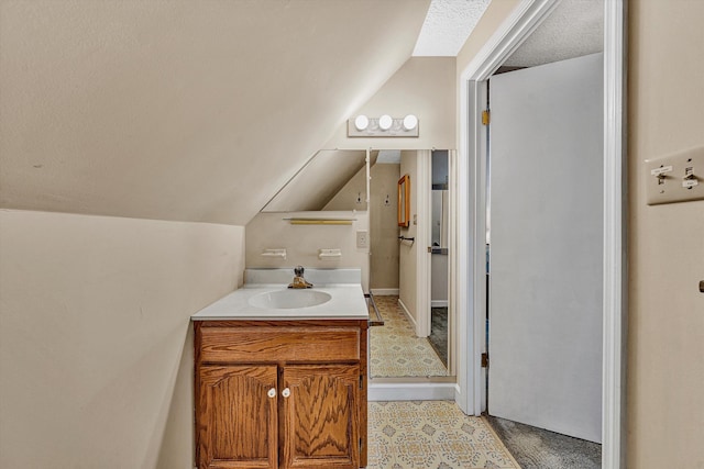 bathroom featuring a textured ceiling, vanity, and lofted ceiling