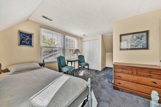 bedroom featuring lofted ceiling, a closet, a textured ceiling, and dark colored carpet