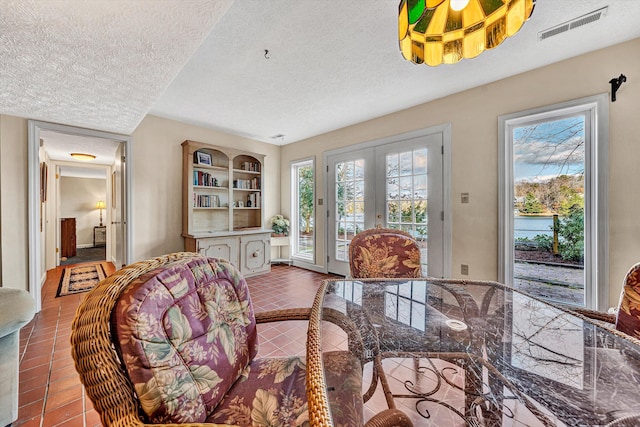 tiled dining room with a textured ceiling, visible vents, and plenty of natural light