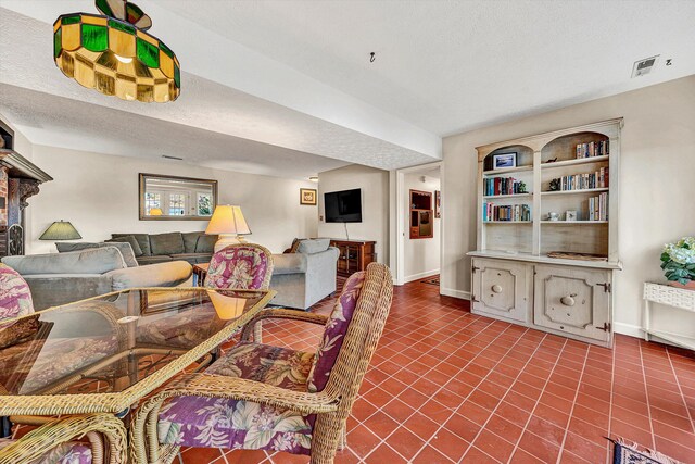 tiled dining space with a textured ceiling, visible vents, and baseboards