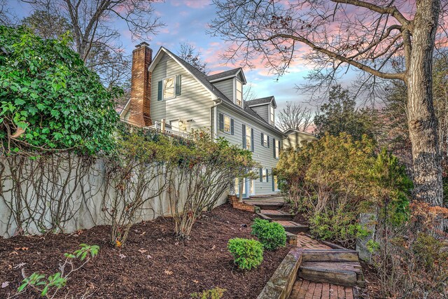 property exterior at dusk featuring a chimney