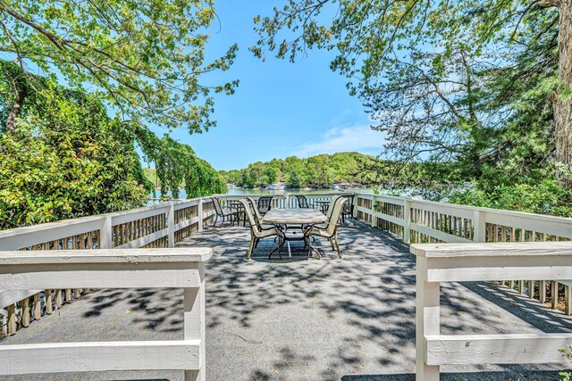 deck with outdoor dining area and a water view