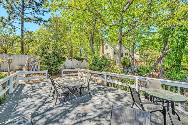 wooden terrace featuring fence, outdoor dining space, and stairway