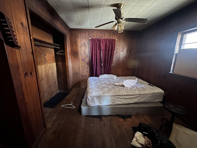 bedroom with dark hardwood / wood-style flooring, wooden walls, and ceiling fan