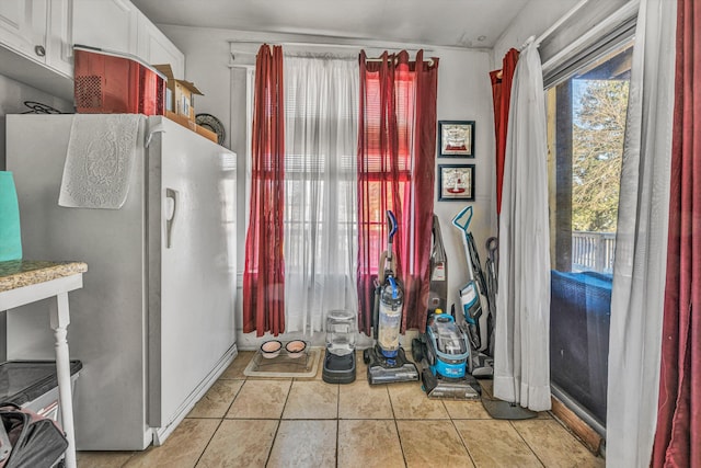 interior space featuring white cabinets, refrigerator, and light tile patterned floors