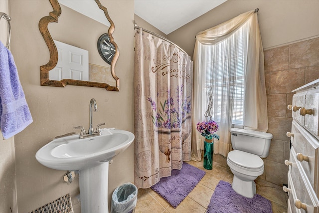 bathroom with a healthy amount of sunlight, tile walls, tile patterned floors, and toilet