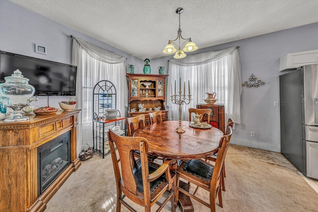 dining area with a textured ceiling, light carpet, and a chandelier