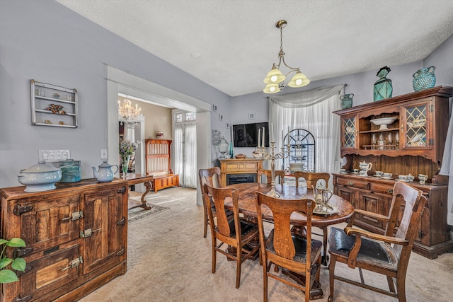 dining area featuring light colored carpet, a notable chandelier, and a textured ceiling