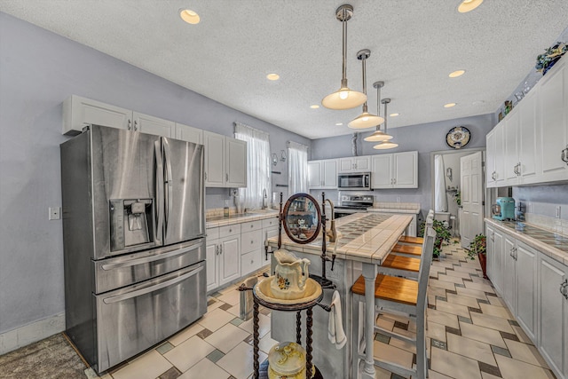 kitchen featuring a center island, stainless steel appliances, a breakfast bar, white cabinets, and sink