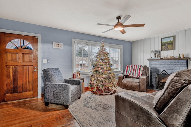 living room with wood-type flooring, a brick fireplace, and ceiling fan