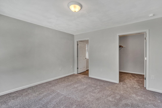 unfurnished bedroom with light carpet, a spacious closet, a closet, and baseboards