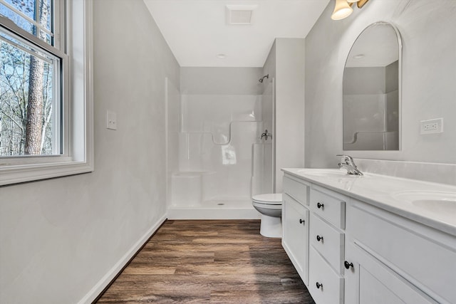 full bath featuring double vanity, toilet, wood finished floors, walk in shower, and a sink