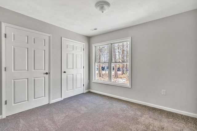 unfurnished bedroom featuring dark colored carpet, visible vents, and baseboards