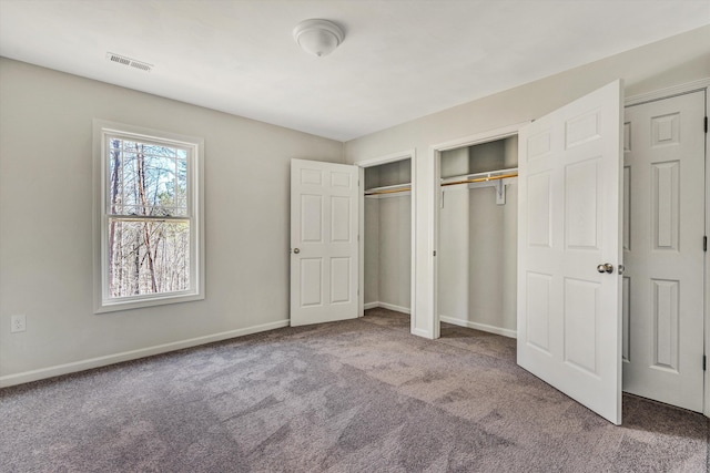 unfurnished bedroom with multiple closets, carpet flooring, visible vents, and baseboards