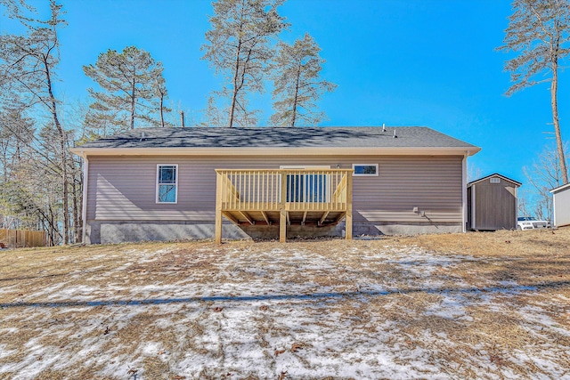 snow covered property with a storage shed and a deck